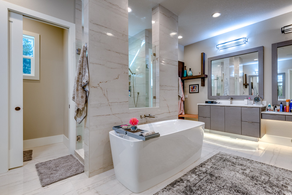 Diseño de cuarto de baño principal actual con armarios con paneles lisos, puertas de armario grises, bañera exenta, ducha empotrada, baldosas y/o azulejos grises, paredes grises, suelo blanco y encimeras blancas