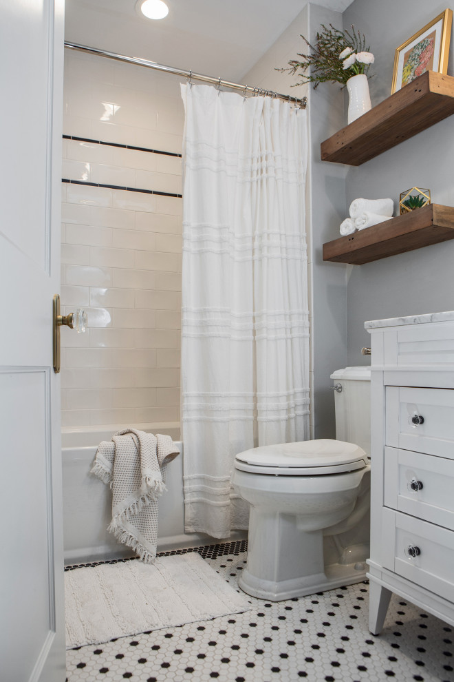 Идея дизайна: ванная комната среднего размера в стиле неоклассика (современная классика) с фасадами островного типа, белыми фасадами, ванной в нише, душем в нише, унитазом-моноблоком, белой плиткой, керамической плиткой, серыми стенами, полом из керамической плитки, душевой кабиной, врезной раковиной, столешницей из искусственного кварца, белым полом, шторкой для ванной, белой столешницей, нишей, тумбой под одну раковину и напольной тумбой