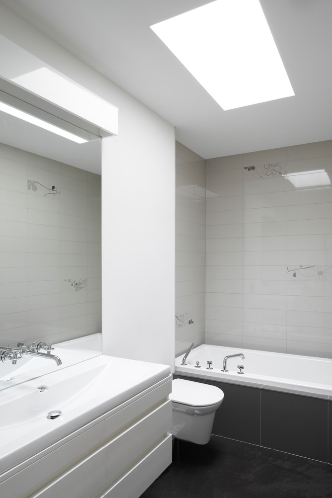 Свежая идея для дизайна: главная ванная комната среднего размера в современном стиле с монолитной раковиной, плоскими фасадами, белыми фасадами, ванной в нише, душем над ванной, инсталляцией, белой плиткой и белыми стенами - отличное фото интерьера