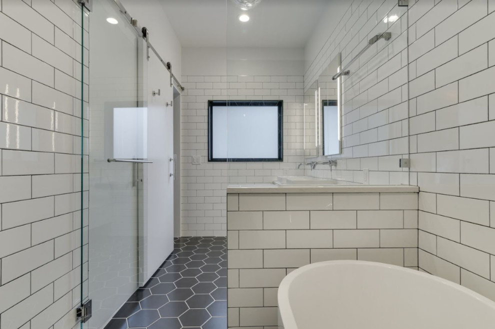 Пример оригинального дизайна: главная ванная комната среднего размера в стиле модернизм с плоскими фасадами, белыми фасадами, отдельно стоящей ванной, душевой комнатой, раздельным унитазом, белой плиткой, плиткой кабанчик, белыми стенами, полом из керамогранита, врезной раковиной, столешницей из искусственного кварца, черным полом, душем с распашными дверями и белой столешницей
