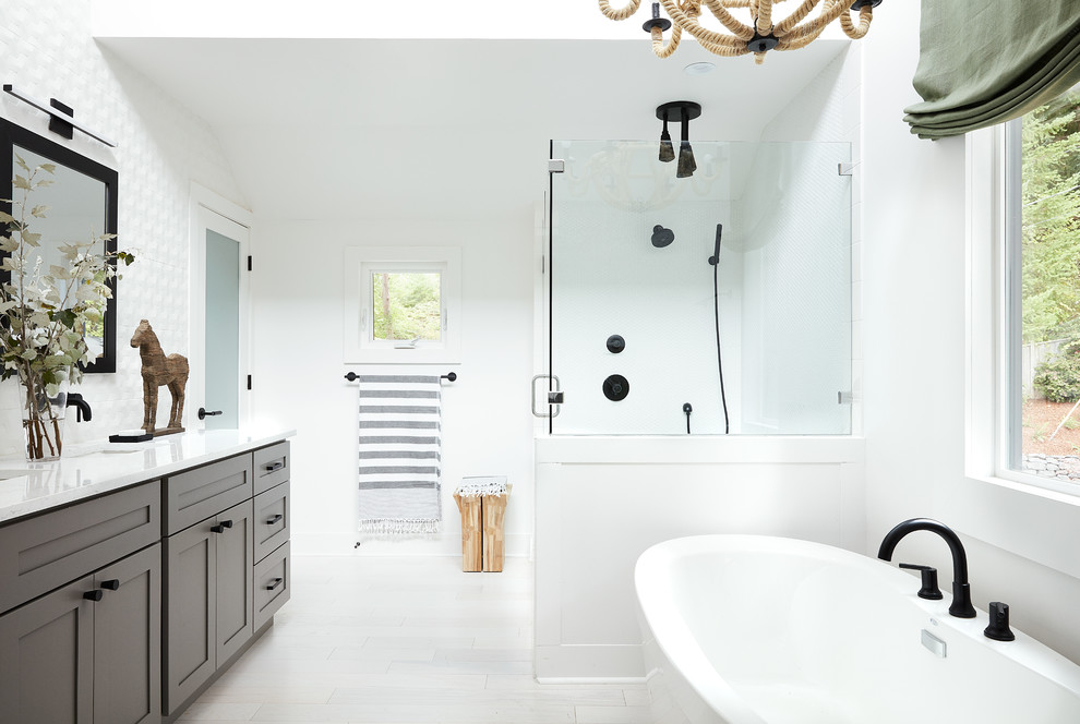 Idée de décoration pour une salle de bain principale champêtre avec un placard à porte shaker, des portes de placard grises, une baignoire indépendante, une douche d'angle, un carrelage blanc, un mur blanc, un lavabo encastré, un sol blanc et une cabine de douche à porte battante.