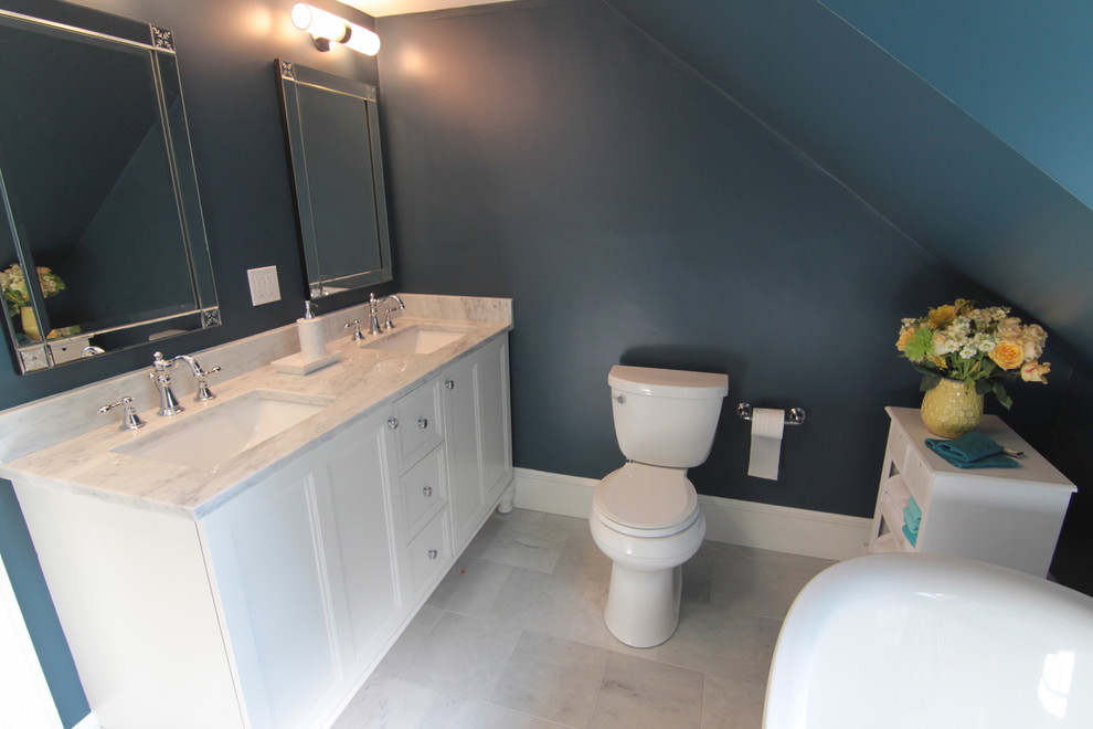 Klassisk inredning av ett litet en-suite badrum, med ett undermonterad handfat, luckor med infälld panel, vita skåp, marmorbänkskiva, ett fristående badkar, en dusch i en alkov, en toalettstol med separat cisternkåpa, grå kakel, stenkakel, blå väggar och marmorgolv