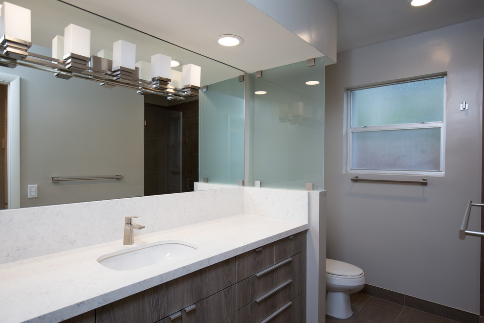 This is an example of a small contemporary family bathroom in Miami with flat-panel cabinets, grey cabinets, an alcove shower, a two-piece toilet, brown tiles, porcelain tiles, grey walls, porcelain flooring, a submerged sink, engineered stone worktops, brown floors and a hinged door.