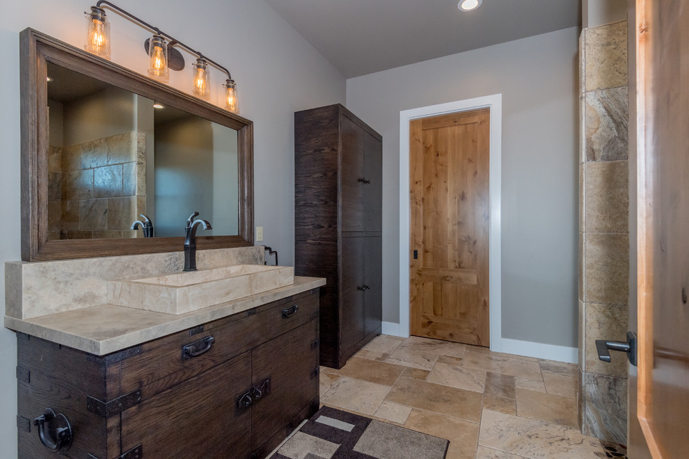 Large mountain style master travertine floor and beige floor bathroom photo in Sacramento with furniture-like cabinets, dark wood cabinets, marble countertops, gray walls, a vessel sink and a two-piece toilet