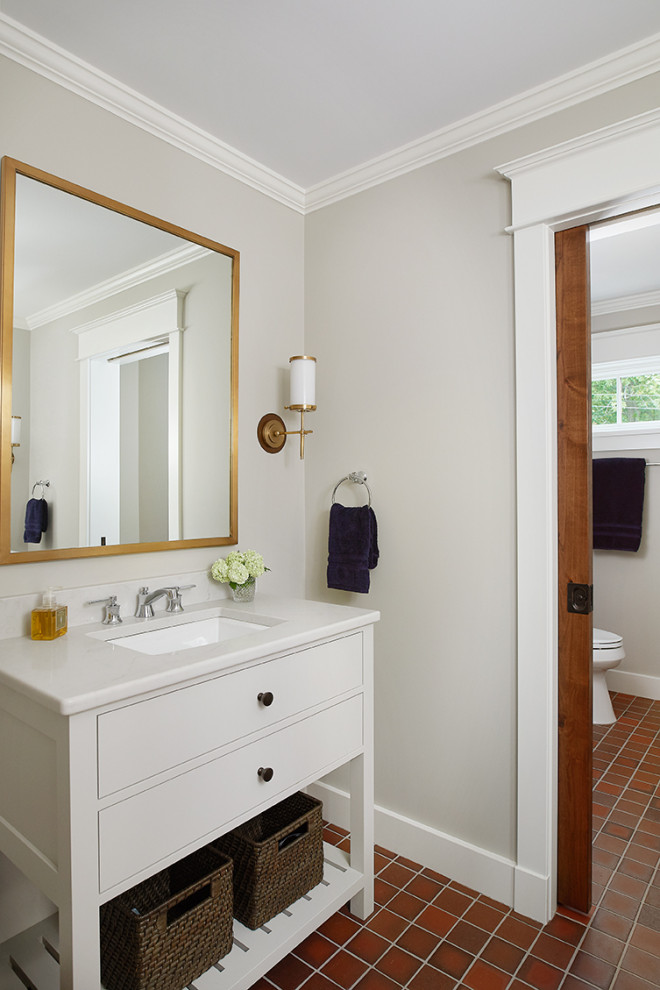 Example of a small beach style 3/4 ceramic tile and brown floor bathroom design in Grand Rapids with flat-panel cabinets, white cabinets, gray walls, an undermount sink, solid surface countertops and white countertops