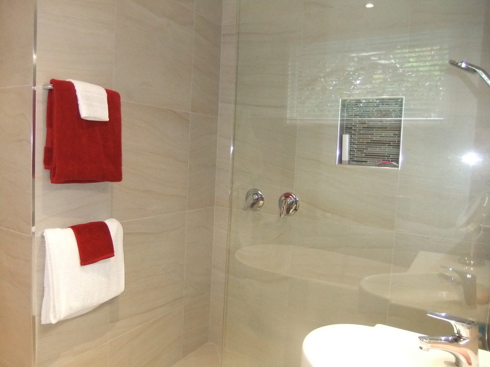 На фото: большая главная ванная комната в стиле модернизм с монолитной раковиной, белыми фасадами, отдельно стоящей ванной, открытым душем, унитазом-моноблоком, бежевой плиткой, керамогранитной плиткой, бежевыми стенами и полом из керамогранита