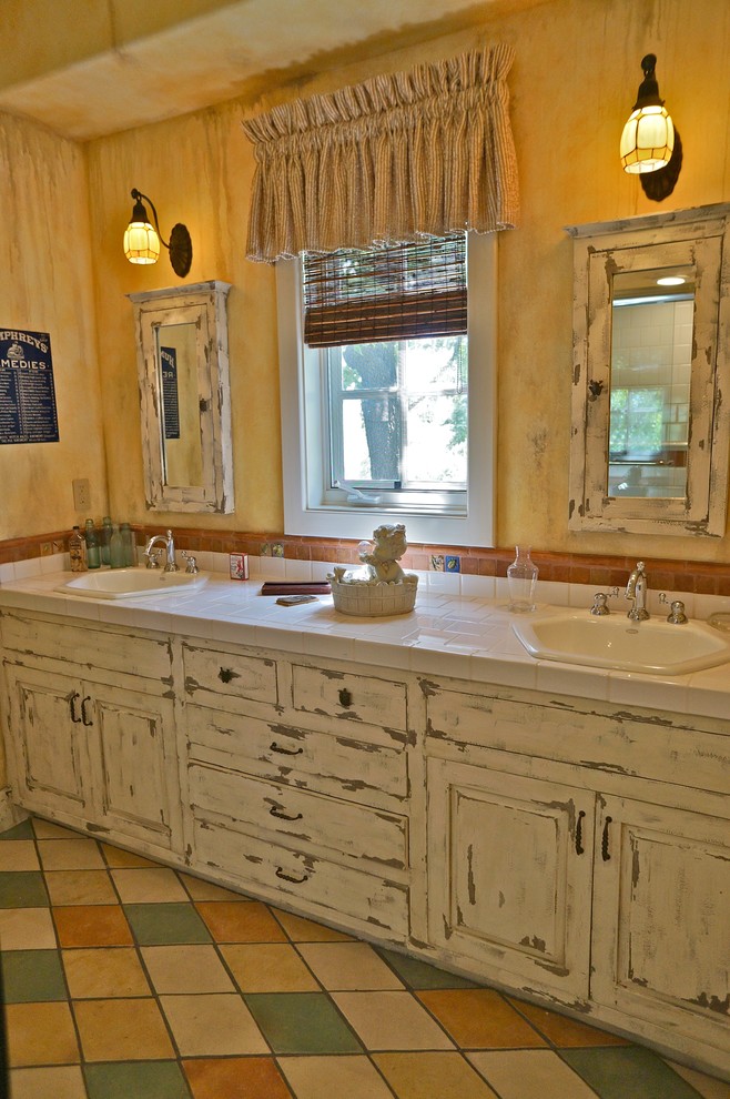 This is an example of a bohemian bathroom in Los Angeles with a built-in sink, raised-panel cabinets, distressed cabinets and multi-coloured tiles.