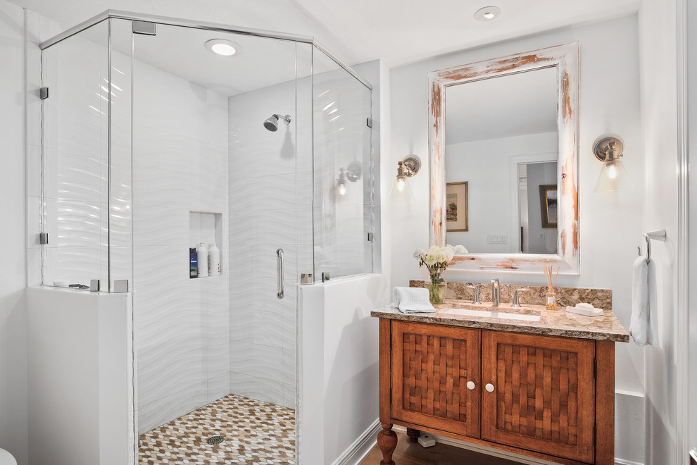 Corner shower - coastal white tile corner shower idea in Miami with medium tone wood cabinets, white walls, an undermount sink, a hinged shower door, brown countertops and recessed-panel cabinets