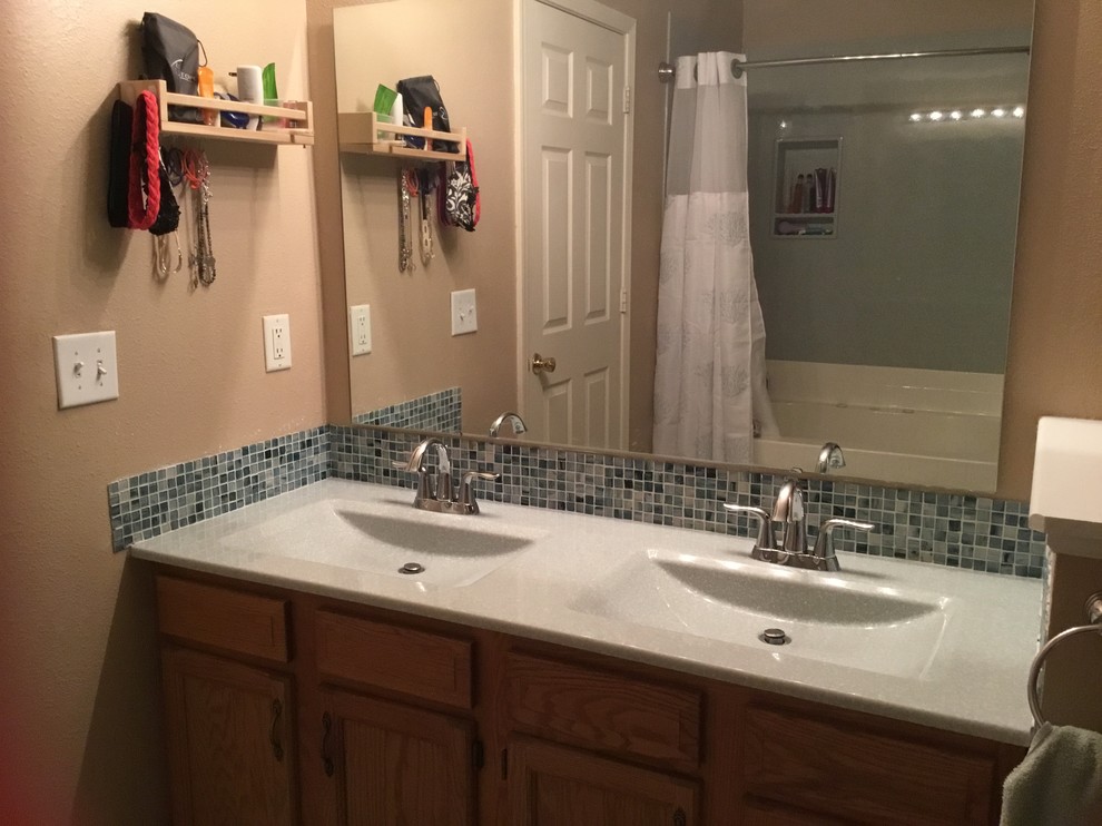 Maritim inredning av ett mellanstort en-suite badrum, med en dusch/badkar-kombination, beige väggar, bänkskiva i akrylsten, blå kakel, glasskiva, ett integrerad handfat och dusch med duschdraperi