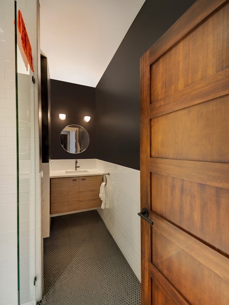 На фото: маленькая ванная комната в современном стиле с плоскими фасадами, фасадами цвета дерева среднего тона, душем в нише, унитазом-моноблоком, белой плиткой, плиткой кабанчик, черными стенами, полом из мозаичной плитки, душевой кабиной, врезной раковиной, столешницей из искусственного кварца, черным полом, душем с распашными дверями и белой столешницей для на участке и в саду с