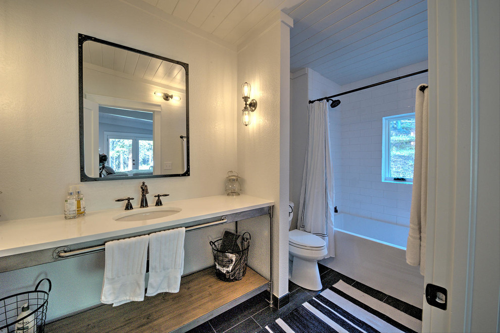 Immagine di una grande stanza da bagno padronale industriale con lavabo sottopiano, vasca/doccia, WC monopezzo, piastrelle bianche e pareti bianche