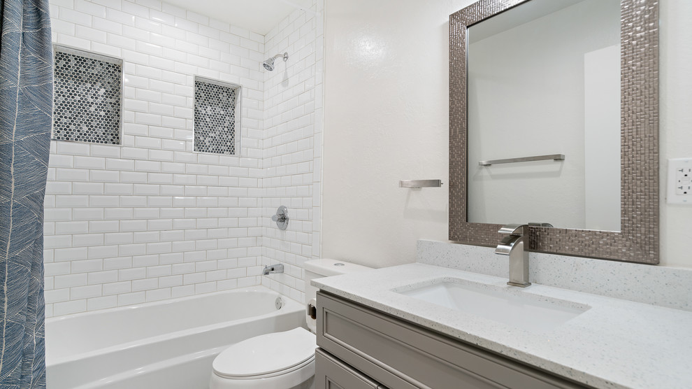 Small classic shower room bathroom in San Francisco with recessed-panel cabinets, grey cabinets, an alcove bath, a shower/bath combination, a two-piece toilet, white tiles, metro tiles, grey walls, a submerged sink, engineered stone worktops, a shower curtain and white worktops.