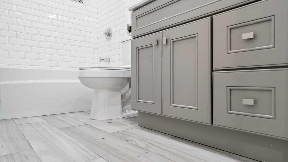 Bathroom - small transitional 3/4 white tile and subway tile porcelain tile and gray floor bathroom idea in San Francisco with recessed-panel cabinets, gray cabinets, a two-piece toilet, gray walls, an undermount sink, quartz countertops and white countertops