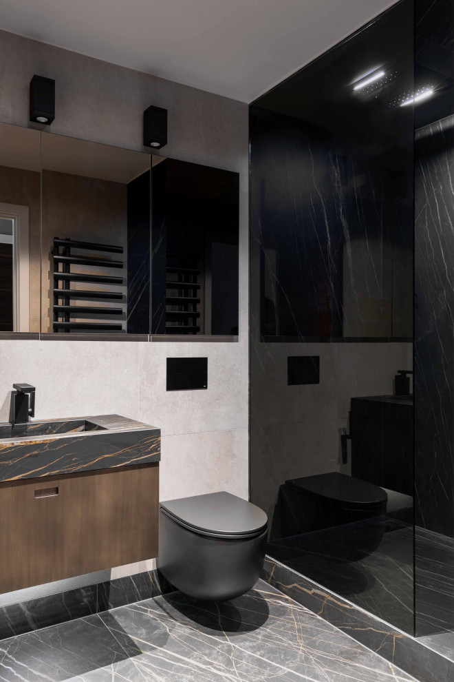 This is an example of a medium sized contemporary ensuite bathroom in London with flat-panel cabinets, brown cabinets, a built-in bath, a walk-in shower, a wall mounted toilet, beige tiles, porcelain tiles, beige walls, porcelain flooring, a wall-mounted sink, tiled worktops, black floors, a hinged door and black worktops.