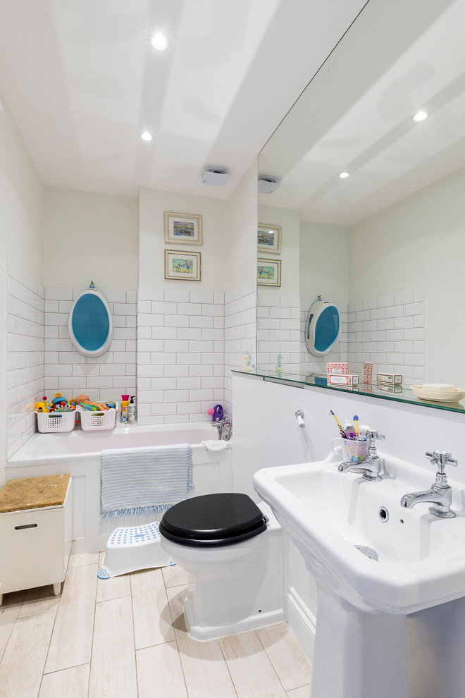 Immagine di una stanza da bagno per bambini classica di medie dimensioni con vasca da incasso, WC monopezzo, piastrelle in ceramica, pareti beige, pavimento con piastrelle in ceramica, lavabo a colonna e pavimento beige