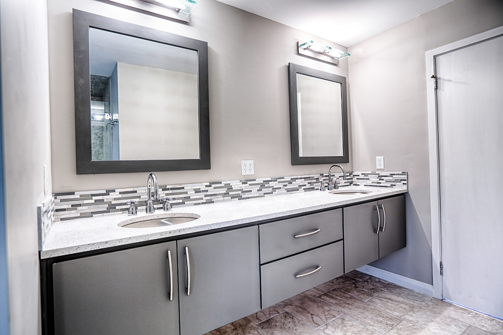 Inredning av ett modernt litet en-suite badrum, med ett undermonterad handfat, släta luckor, grå skåp, bänkskiva i kvarts, grå kakel, glaskakel, grå väggar och klinkergolv i porslin