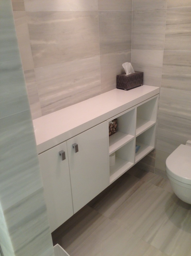 Modern inredning av ett mellanstort en-suite badrum, med ett undermonterad handfat, släta luckor, vita skåp, bänkskiva i kvarts, en vägghängd toalettstol, vit kakel, stenkakel, klinkergolv i porslin, en dubbeldusch och grå väggar