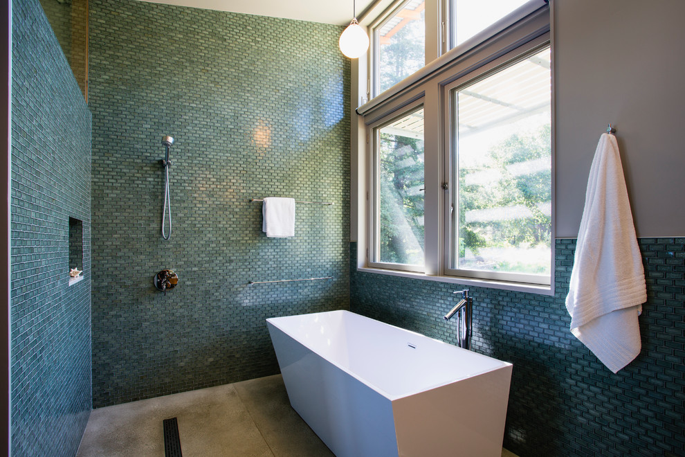 На фото: большая главная ванная комната в современном стиле с отдельно стоящей ванной, открытым душем, стеклянной плиткой, синей плиткой, синими стенами, бетонным полом и открытым душем