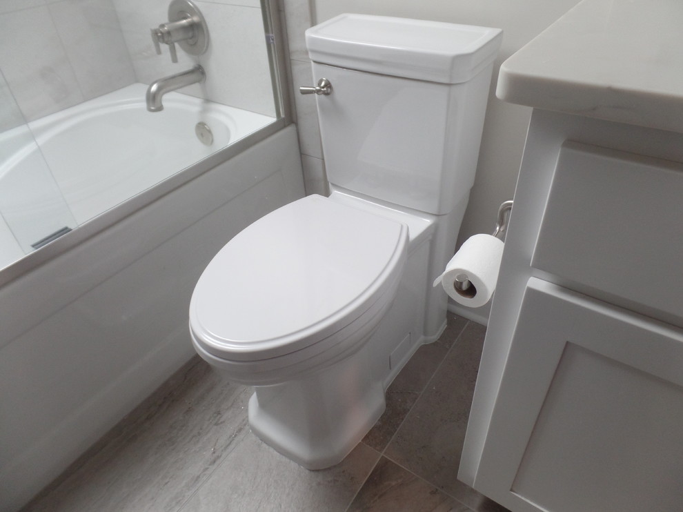 Design ideas for a medium sized contemporary family bathroom in Other with shaker cabinets, white cabinets, an alcove bath, a shower/bath combination, a two-piece toilet, grey tiles, porcelain tiles, grey walls, porcelain flooring, a submerged sink, engineered stone worktops and grey floors.