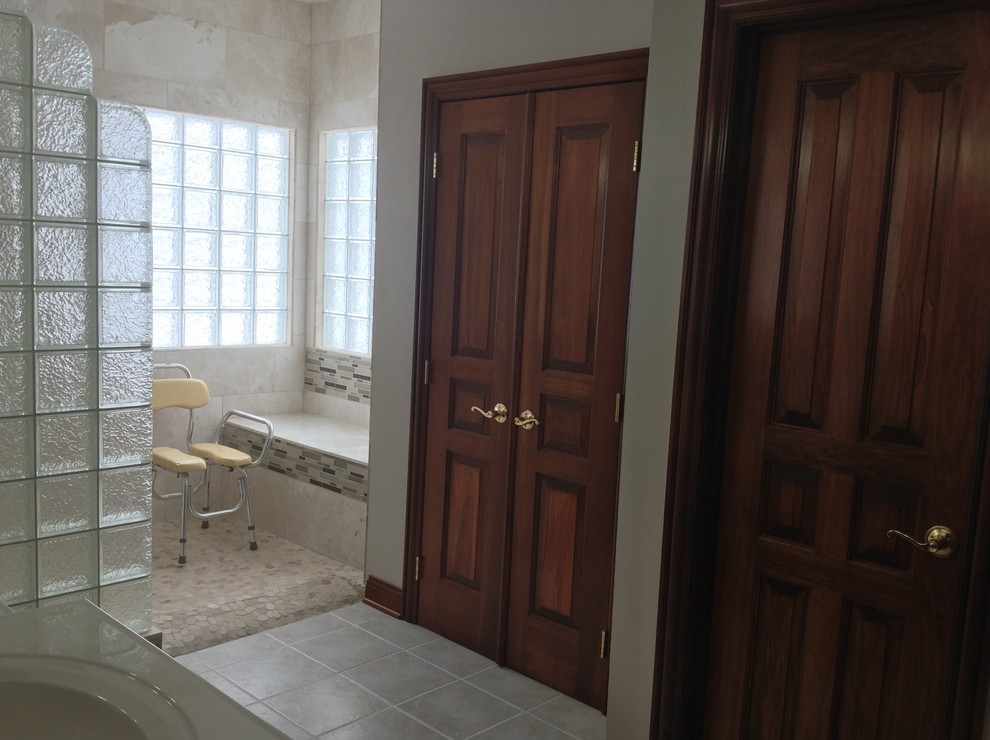 Inspiration pour une grande salle de bain principale traditionnelle en bois foncé avec un placard avec porte à panneau encastré, un plan de toilette en surface solide, une douche ouverte, une plaque de galets, un mur beige et un sol en carrelage de céramique.