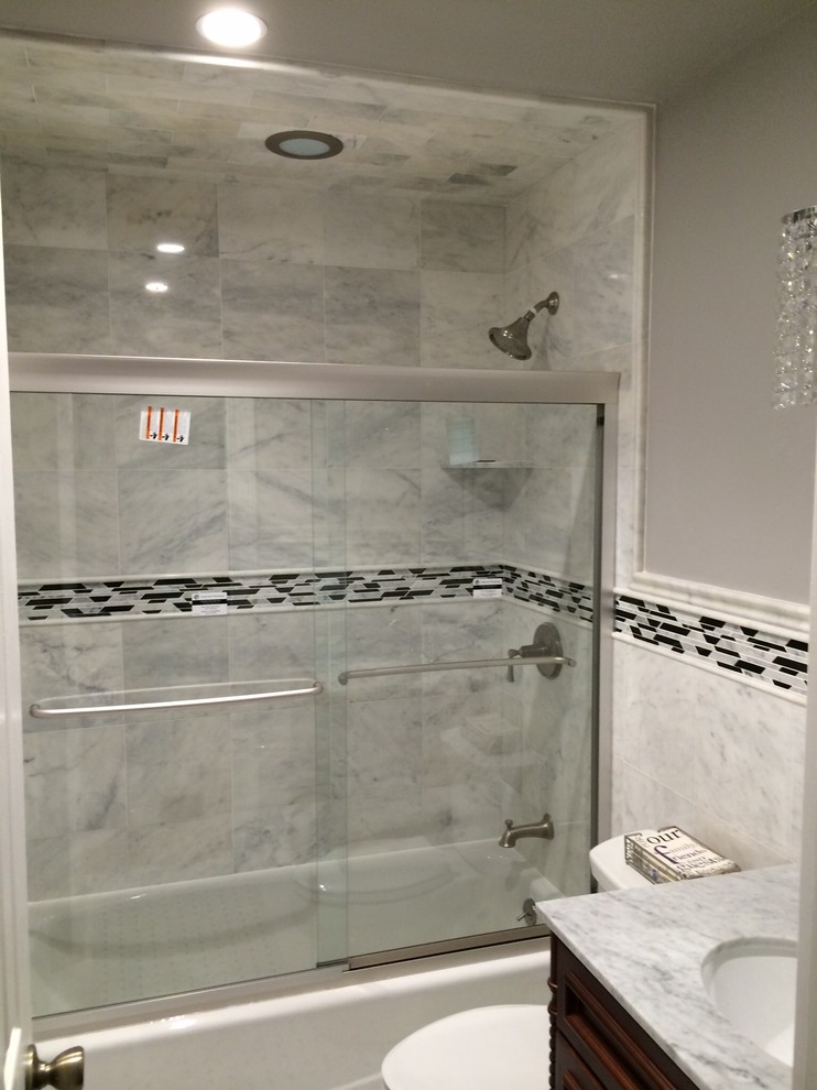 Стильный дизайн: большая ванная комната в современном стиле с фасадами островного типа, темными деревянными фасадами, ванной в нише, раздельным унитазом, белой плиткой, каменной плиткой, серыми стенами, полом из мозаичной плитки, врезной раковиной и мраморной столешницей - последний тренд