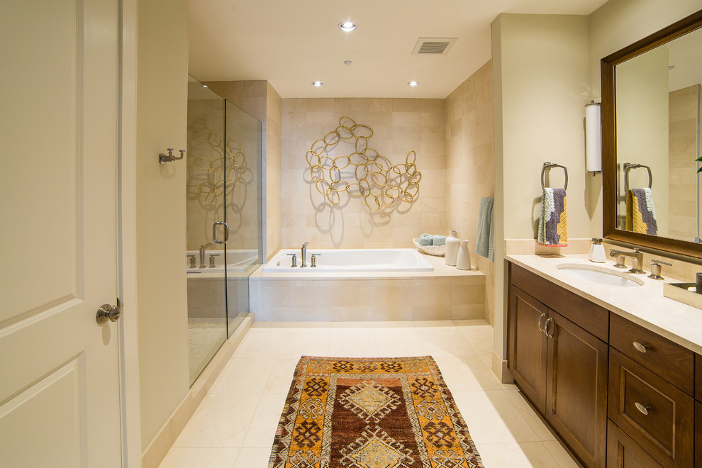 Immagine di una stanza da bagno classica con lavabo sottopiano, ante con riquadro incassato, ante in legno scuro, top in superficie solida, vasca da incasso, piastrelle beige e piastrelle in pietra