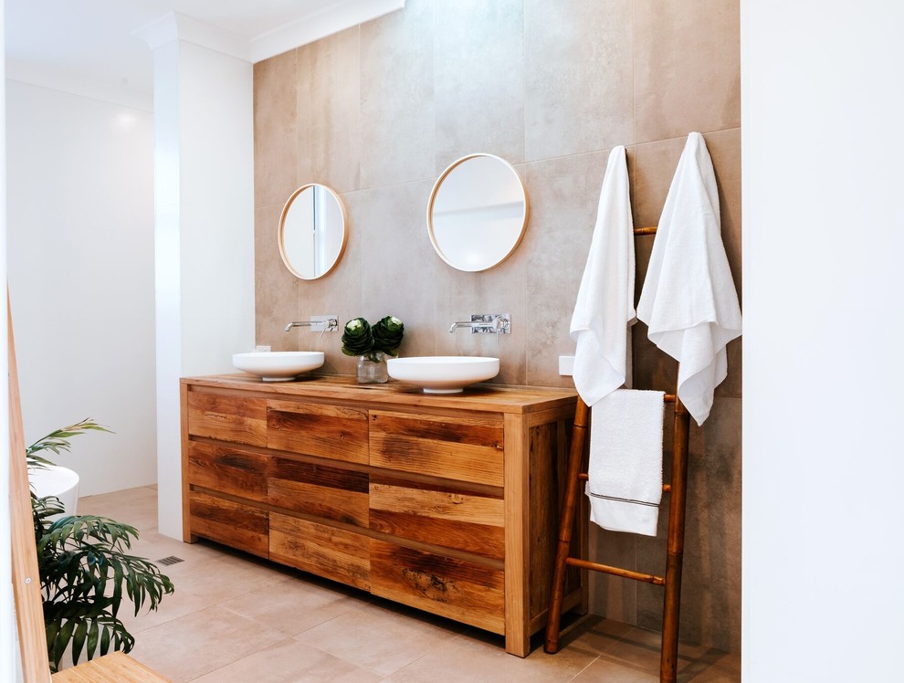 Пример оригинального дизайна: большая главная ванная комната в современном стиле с плоскими фасадами, фасадами цвета дерева среднего тона, отдельно стоящей ванной, раздельным унитазом, бежевой плиткой, керамической плиткой, бежевыми стенами, полом из керамической плитки, настольной раковиной, столешницей из дерева, бежевым полом и коричневой столешницей