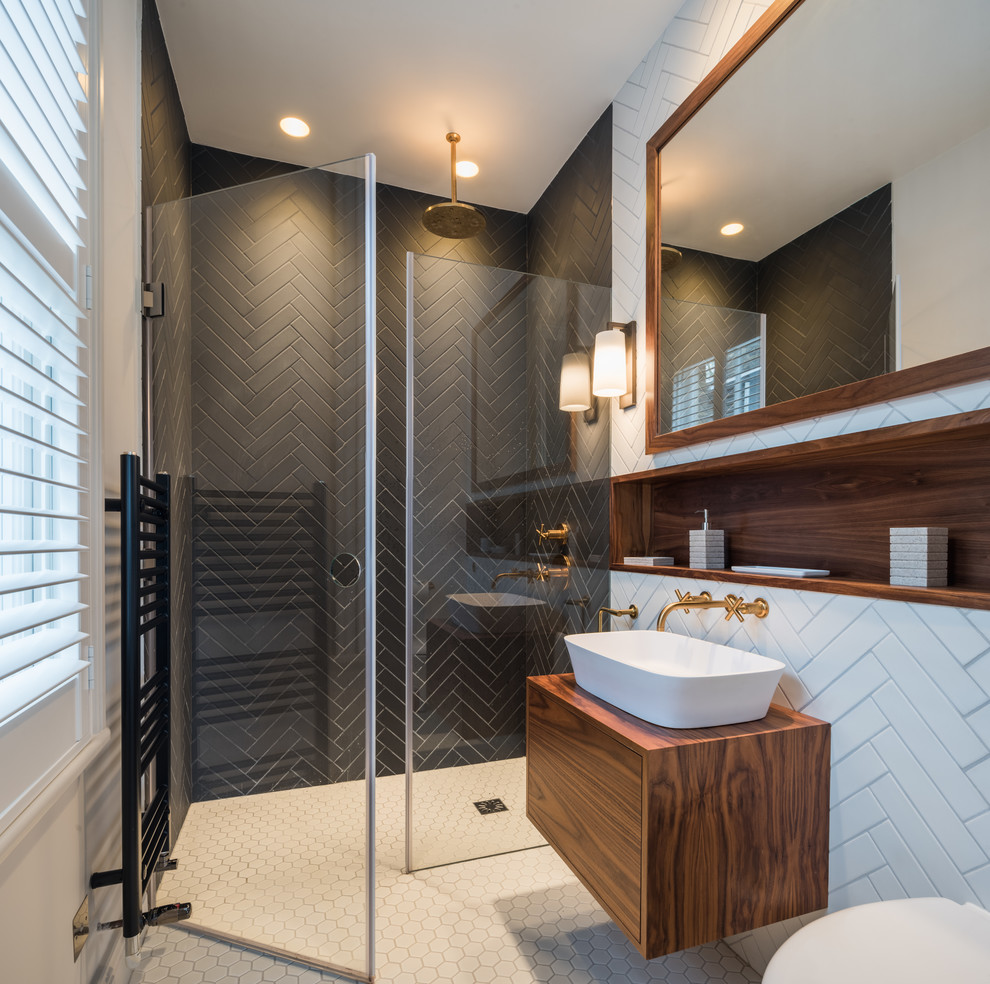 Foto på ett mellanstort funkis brun badrum, med släta luckor, bruna skåp, en öppen dusch, svart och vit kakel, ett fristående handfat, vitt golv, dusch med gångjärnsdörr, en vägghängd toalettstol, vita väggar och träbänkskiva