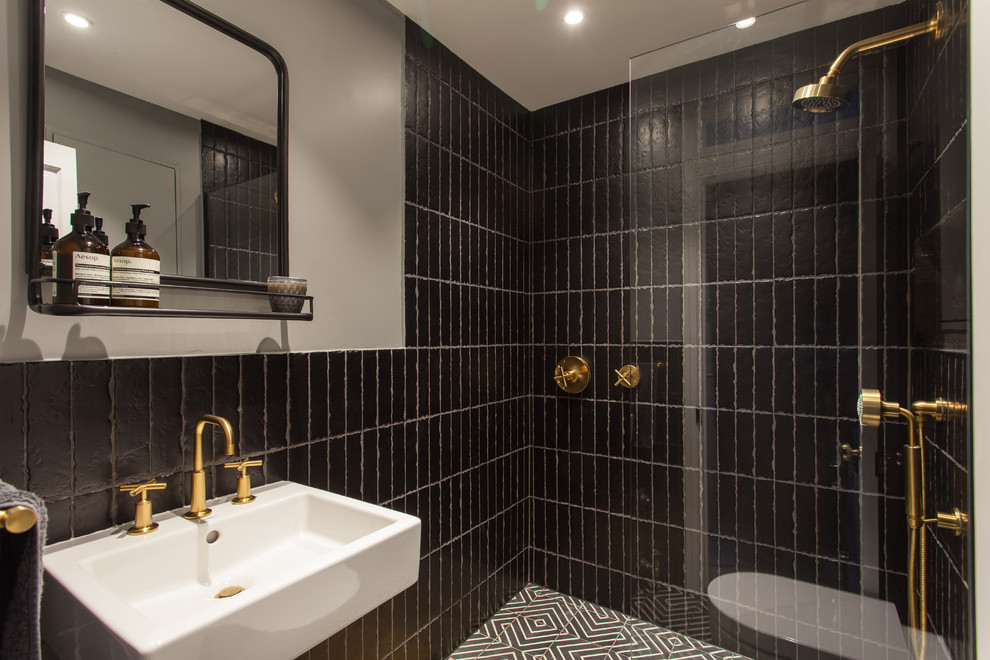 Modelo de cuarto de baño actual pequeño con ducha empotrada, baldosas y/o azulejos negros, paredes grises, aseo y ducha, lavabo suspendido, suelo negro y ducha abierta