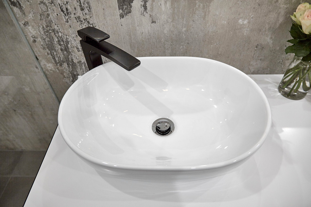 Inredning av ett industriellt litet badrum, med svarta skåp, ett fristående badkar, en öppen dusch, en vägghängd toalettstol, porslinskakel, klinkergolv i porslin och ett fristående handfat