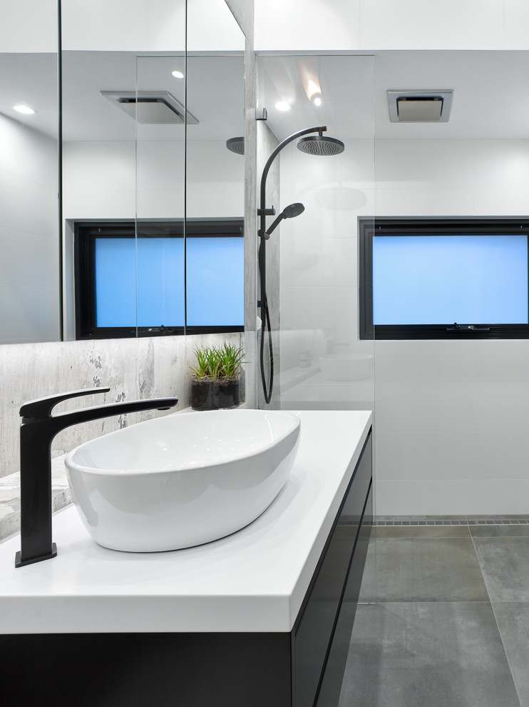 Cette photo montre une petite salle de bain industrielle avec des portes de placard noires, une douche ouverte, des carreaux de porcelaine, un sol en carrelage de porcelaine, une vasque et un plan de toilette en surface solide.