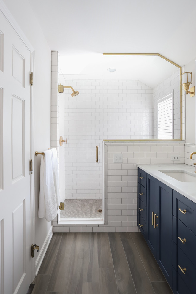 Elegant white tile and subway tile brown floor alcove shower photo in Minneapolis with shaker cabinets, blue cabinets, white walls, an undermount sink, a hinged shower door and white countertops