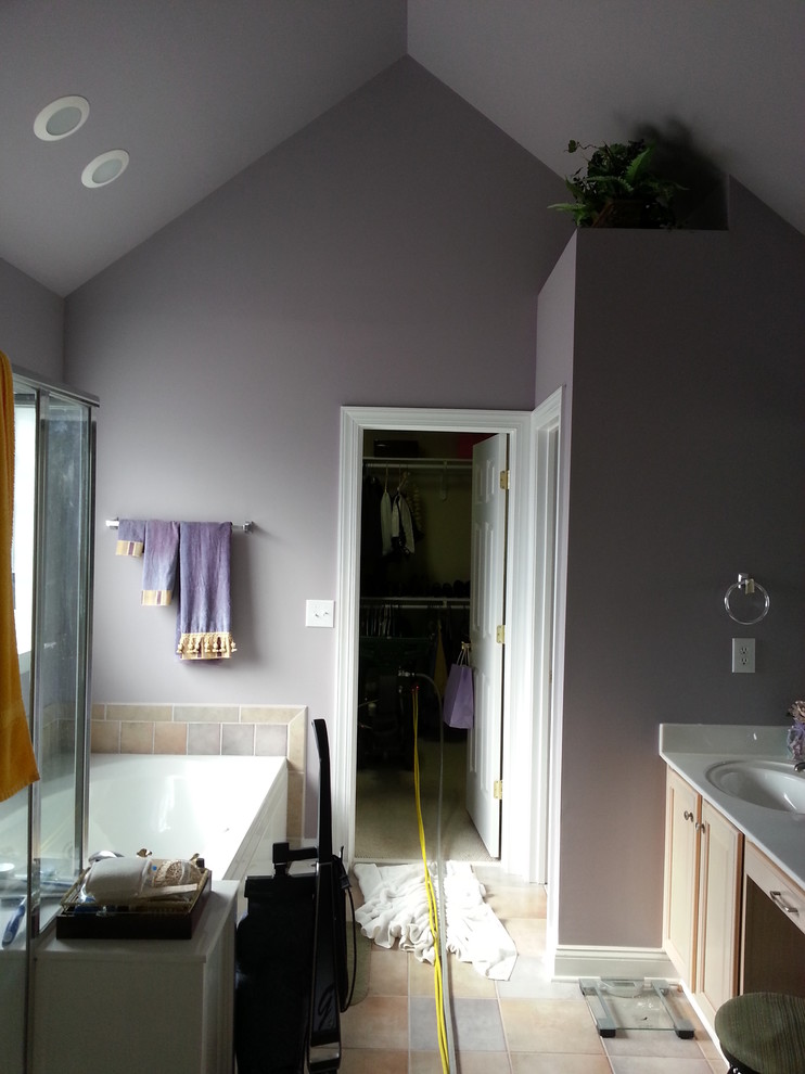 Foto de cuarto de baño principal tradicional grande con armarios con paneles empotrados, puertas de armario de madera clara, encimera de mármol, bañera empotrada, ducha esquinera, sanitario de una pieza, baldosas y/o azulejos beige, baldosas y/o azulejos de porcelana, paredes púrpuras y suelo de baldosas de porcelana