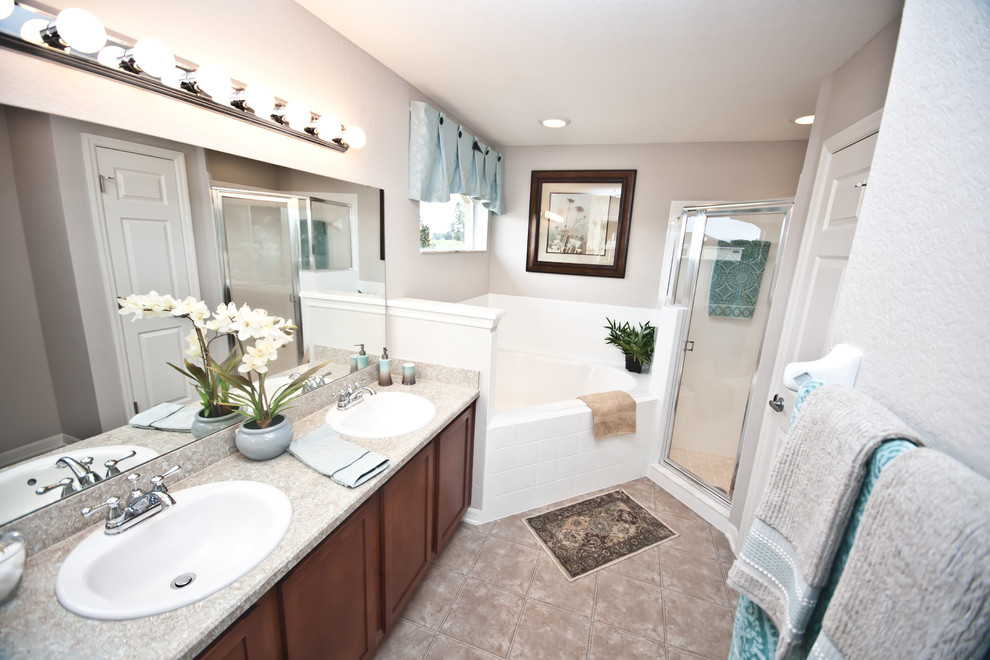 Design ideas for a medium sized ensuite bathroom in Tampa with recessed-panel cabinets, medium wood cabinets, laminate worktops, a corner bath, an alcove shower, beige tiles, grey walls and lino flooring.