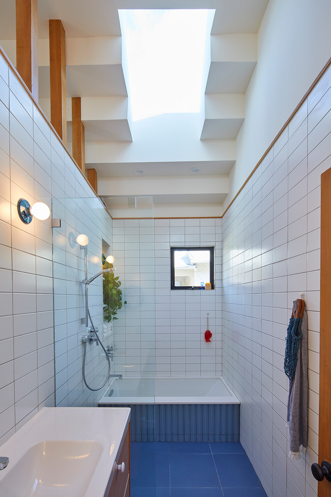 Exempel på ett modernt badrum, med släta luckor, skåp i mellenmörkt trä, ett undermonterat badkar, en kantlös dusch, vit kakel, tunnelbanekakel, vita väggar, ett konsol handfat, blått golv och med dusch som är öppen