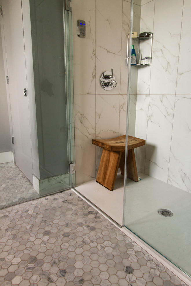 Exempel på ett stort klassiskt vit vitt en-suite badrum, med luckor med glaspanel, vita skåp, en kantlös dusch, en toalettstol med separat cisternkåpa, grå kakel, stenkakel, grå väggar, marmorgolv, ett väggmonterat handfat, bänkskiva i akrylsten, grått golv och dusch med gångjärnsdörr