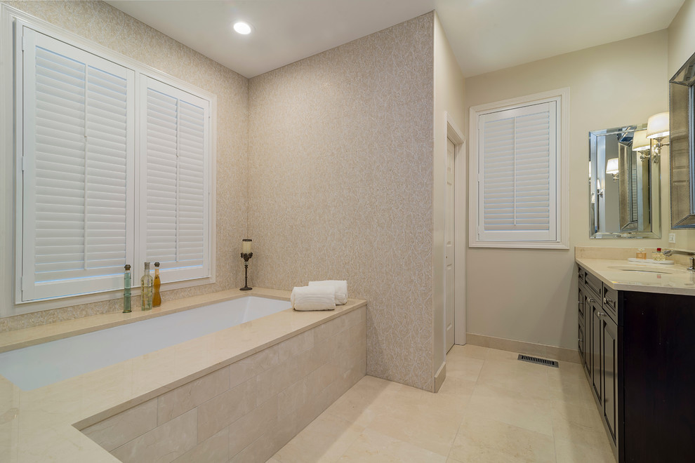 Bild på ett stort vintage en-suite badrum, med ett undermonterad handfat, luckor med upphöjd panel, skåp i mörkt trä, marmorbänkskiva, ett undermonterat badkar, en hörndusch, beige kakel, stenhäll, beige väggar och marmorgolv