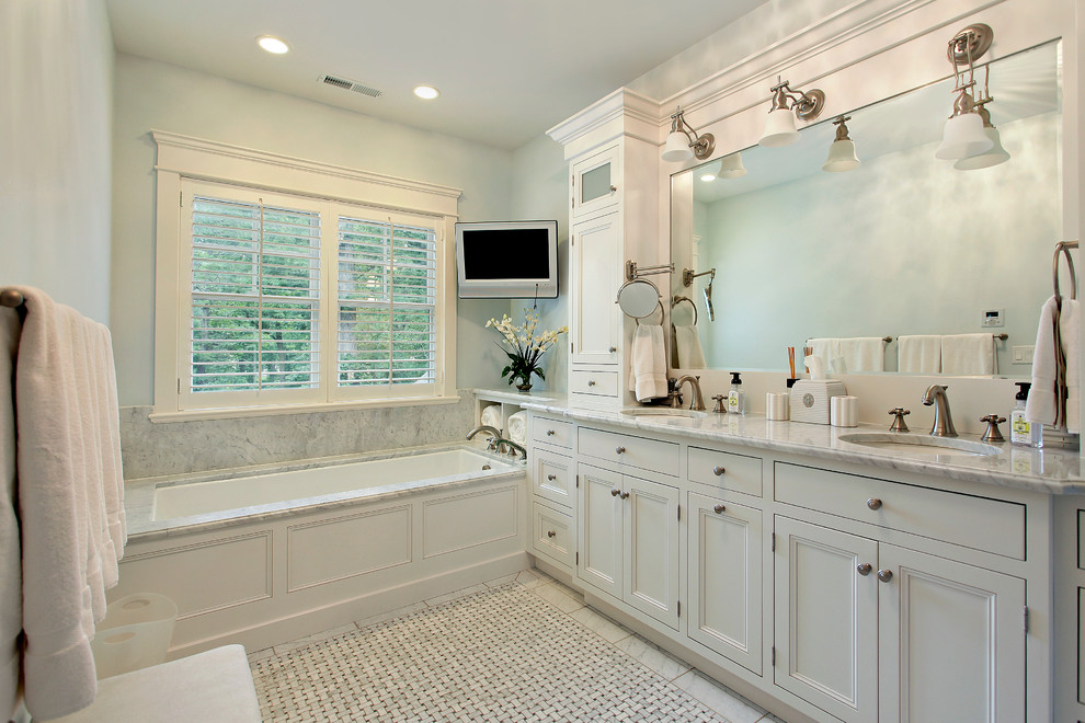 Diseño de cuarto de baño clásico con lavabo bajoencimera, armarios con paneles empotrados, puertas de armario blancas y bañera empotrada