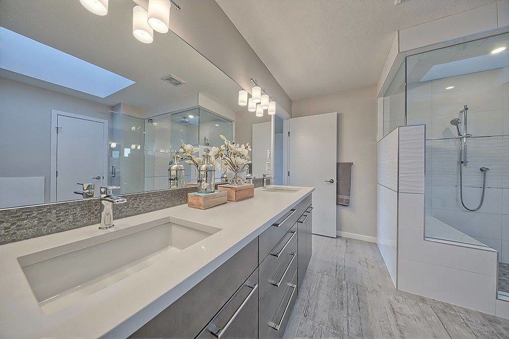 Großes Modernes Badezimmer En Suite mit grauer Wandfarbe, Sperrholzboden, Einbaubadewanne, Eckdusche, Unterbauwaschbecken, Quarzwerkstein-Waschtisch, flächenbündigen Schrankfronten, grauen Schränken, grauem Boden und Falttür-Duschabtrennung in Calgary
