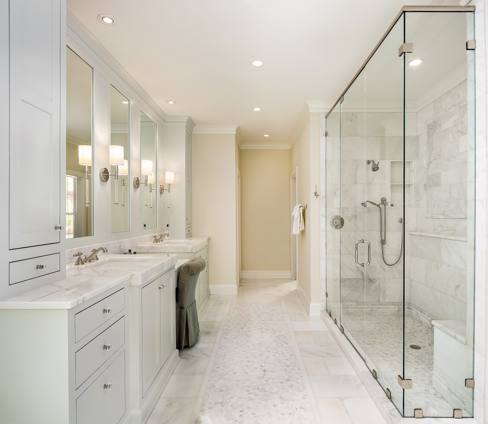 Cette image montre une grande salle de bain principale traditionnelle avec un placard à porte shaker, une baignoire indépendante, une douche d'angle, du carrelage en marbre, un sol en marbre, un lavabo encastré, un plan de toilette en marbre et une cabine de douche à porte battante.