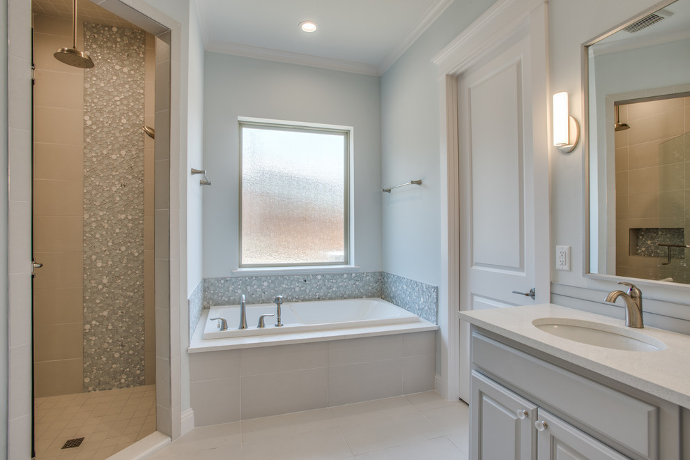 This is an example of a medium sized classic ensuite bathroom in Dallas with raised-panel cabinets, grey cabinets, a one-piece toilet, a submerged sink, a built-in bath, an alcove shower, grey walls and a hinged door.