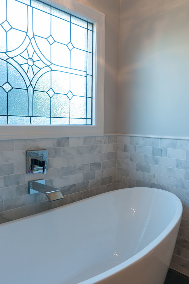 Inredning av ett klassiskt stort en-suite badrum, med luckor med upphöjd panel, vita skåp, ett fristående badkar, en hörndusch, grå kakel, glaskakel, grå väggar, klinkergolv i porslin, ett undermonterad handfat och marmorbänkskiva