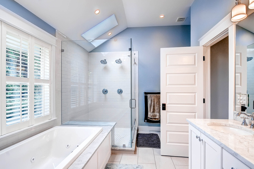 デンバーにある低価格の中くらいなトラディショナルスタイルのおしゃれなマスターバスルーム (落し込みパネル扉のキャビネット、白いキャビネット、大理石の洗面台、ドロップイン型浴槽、コーナー設置型シャワー、一体型トイレ	、白いタイル、セラミックタイル、青い壁、磁器タイルの床) の写真