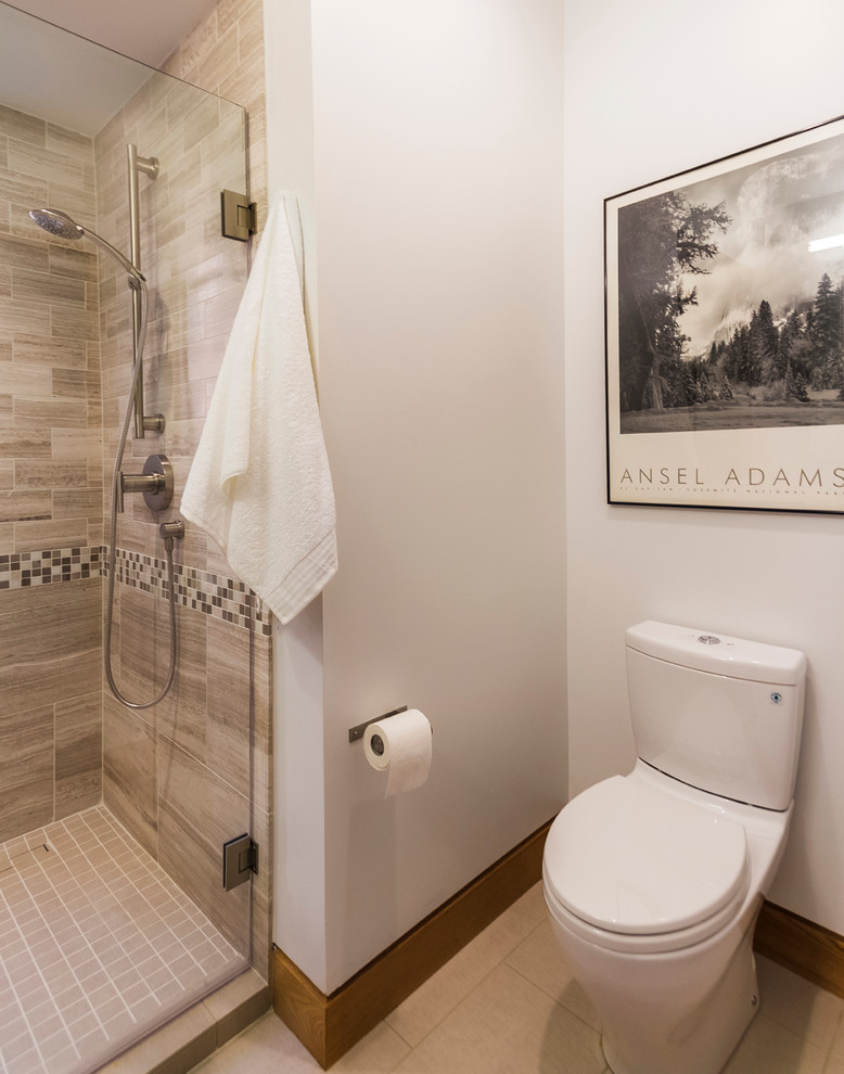 Photo of a small contemporary bathroom in Denver with a submerged sink, flat-panel cabinets, medium wood cabinets, quartz worktops, a one-piece toilet, beige tiles, stone tiles, white walls and porcelain flooring.