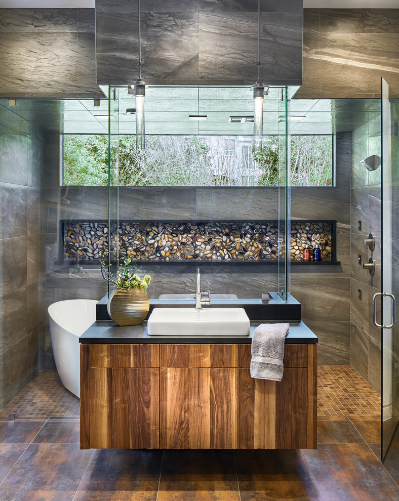 Идея дизайна: главная ванная комната в современном стиле с плоскими фасадами, фасадами цвета дерева среднего тона, отдельно стоящей ванной, душем без бортиков, серой плиткой, разноцветной плиткой, галечной плиткой и настольной раковиной