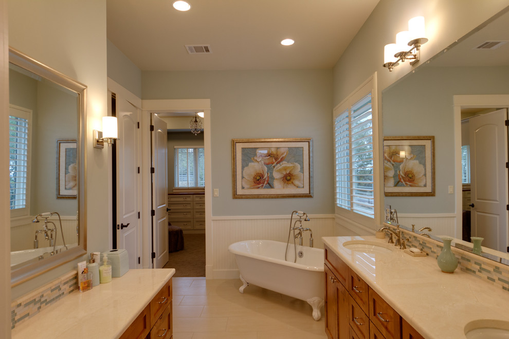 Bild på ett mellanstort amerikanskt vit vitt en-suite badrum, med ett undermonterad handfat, luckor med infälld panel, skåp i mellenmörkt trä, ett badkar med tassar, blå kakel, glaskakel, blå väggar, klinkergolv i keramik, bänkskiva i akrylsten och vitt golv
