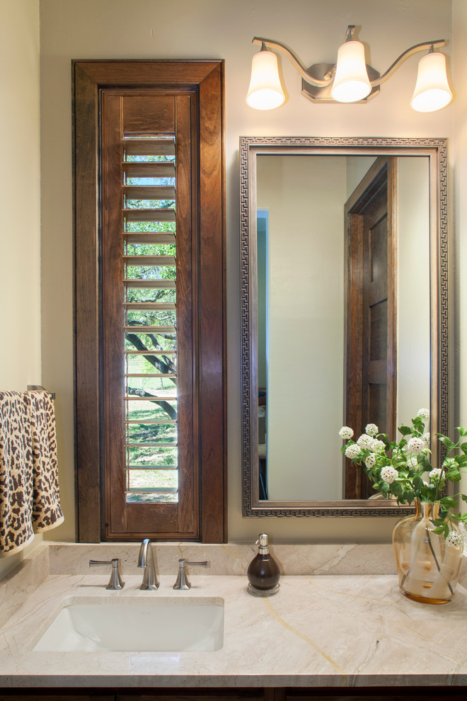 Réalisation d'une petite salle de bain tradition en bois brun avec un lavabo encastré, un placard avec porte à panneau surélevé, un plan de toilette en marbre, un carrelage beige, un carrelage de pierre et un mur beige.