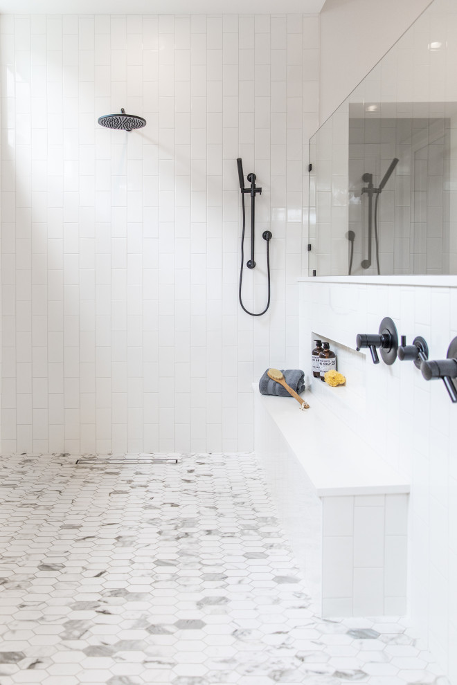 На фото: огромная главная ванная комната в стиле модернизм с плоскими фасадами, светлыми деревянными фасадами, отдельно стоящей ванной, двойным душем, раздельным унитазом, белой плиткой, каменной плиткой, белыми стенами, полом из керамогранита, настольной раковиной, столешницей из гранита, белым полом, открытым душем и черной столешницей с