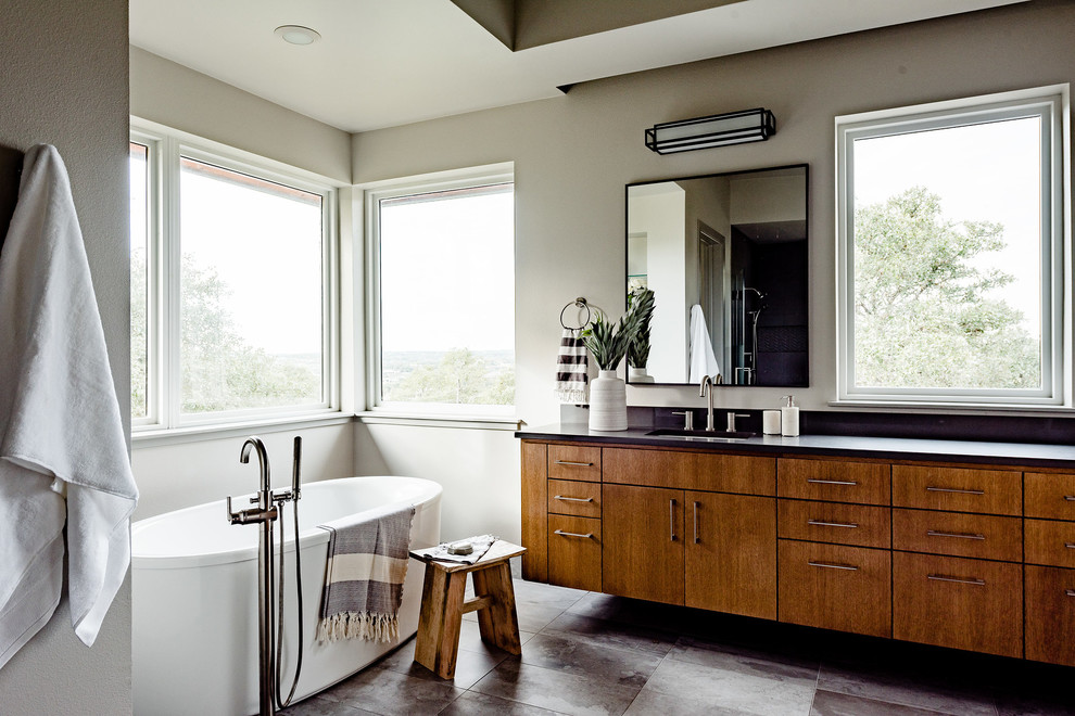 Идея дизайна: главная ванная комната среднего размера в современном стиле с плоскими фасадами, коричневыми фасадами, отдельно стоящей ванной и черной столешницей