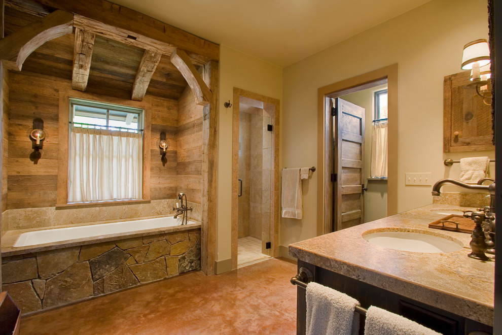 Aménagement d'une grande salle de bain principale montagne en bois foncé avec une baignoire posée, un carrelage beige et un mur beige.